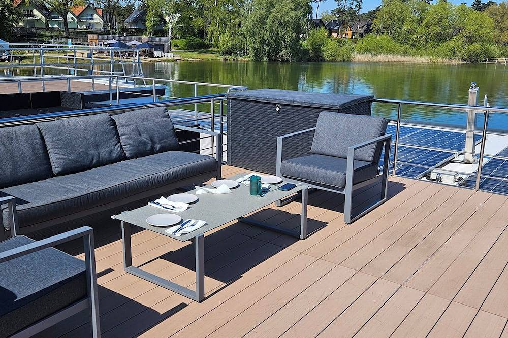 Modernes festliegendes Hausboot mit großzügiger Dachterrasse und Ruderboot in Röbel, Müritz