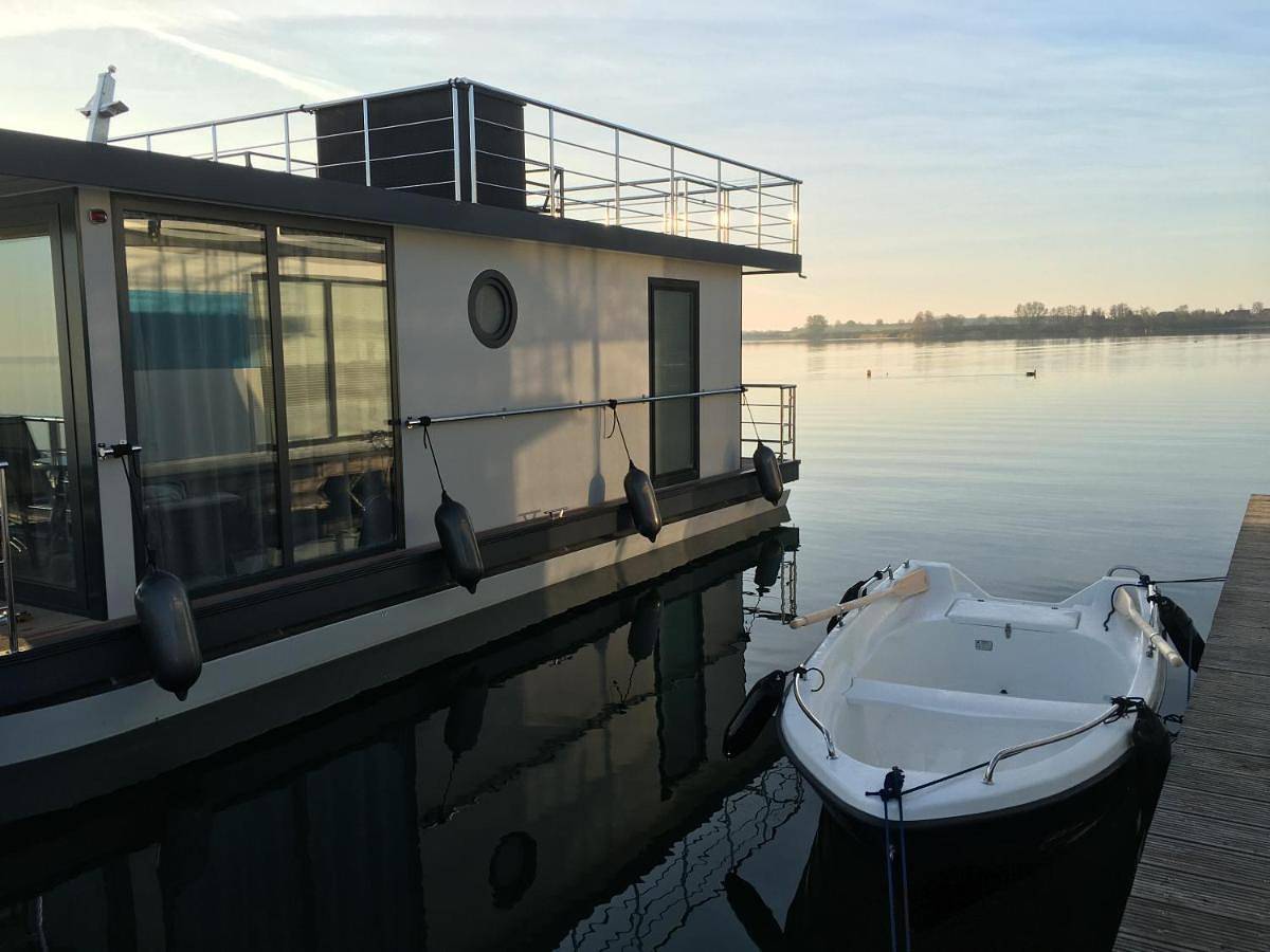Modernes festliegendes Hausboot mit großzügiger Dachterrasse und Ruderboot in Röbel, Müritz