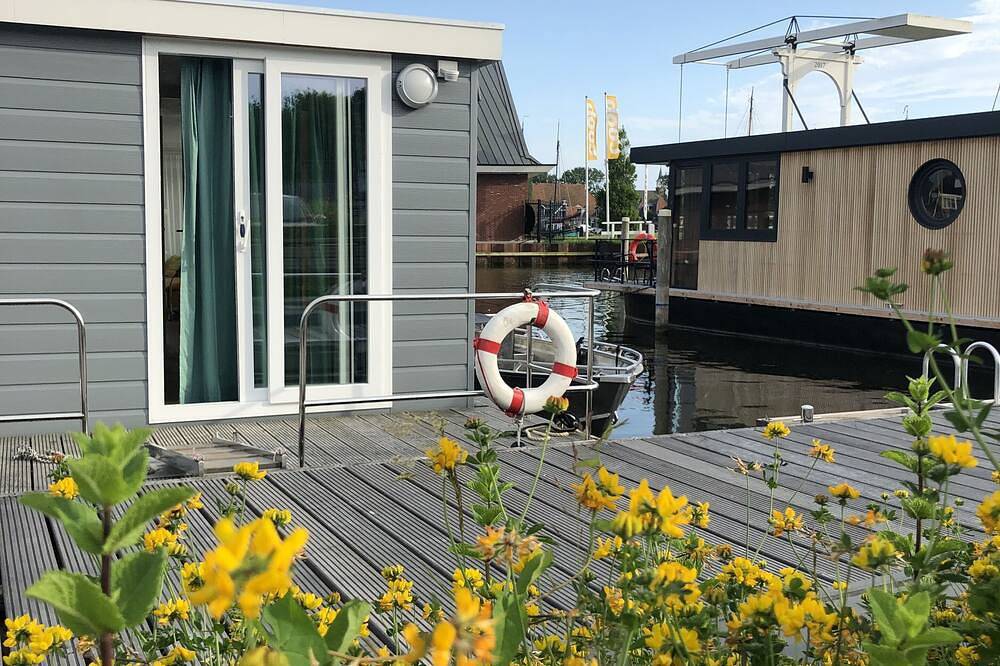 Modern houseboat in quiet harbor close to the Ijsselmeer with Sups and canoe in Stavoren, IJsselmeer