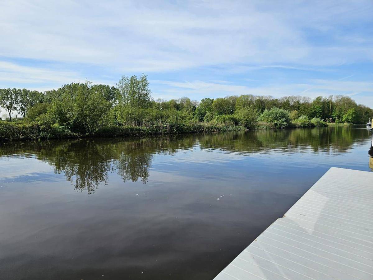 Luxe woonboot in de natuur aan doorgaand vaarwater in Leeuwarden, Nederlandse Noordzeekust