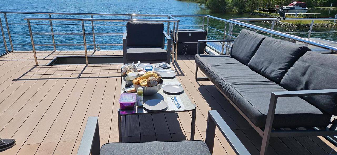 Modernes festliegendes Hausboot mit großzügiger Dachterrasse und Ruderboot in Röbel, Müritz