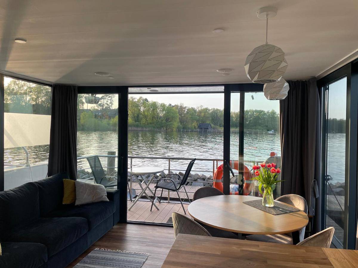 Modernes festliegendes Hausboot mit großzügiger Dachterrasse und Ruderboot in Röbel, Müritz