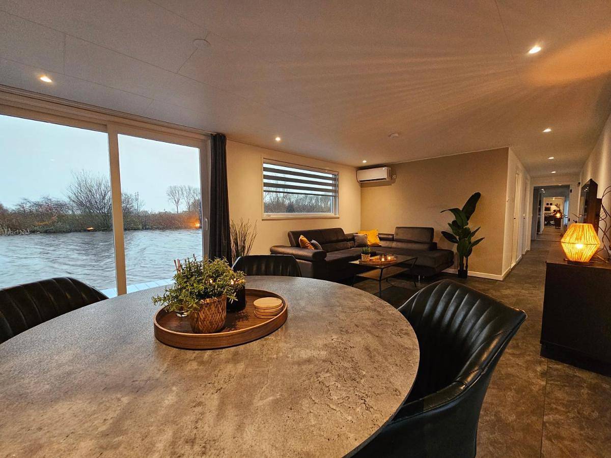 Luxe woonboot in de natuur aan doorgaand vaarwater in Leeuwarden, Nederlandse Noordzeekust